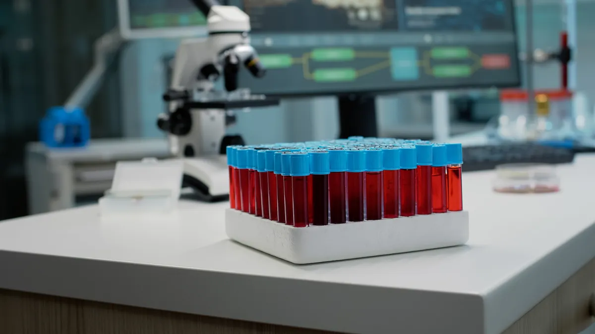 Blood samples beside a microscope and diagnostic screens in a laboratory