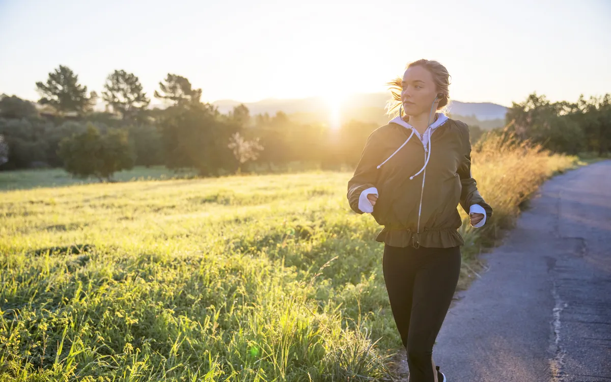 A woman running along a rural road at sunrise