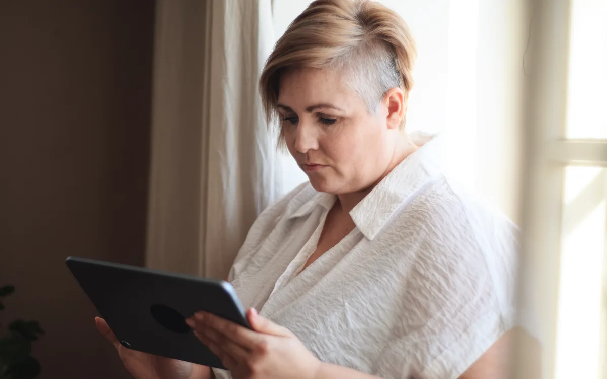 A woman by a window reading her results on a tablet