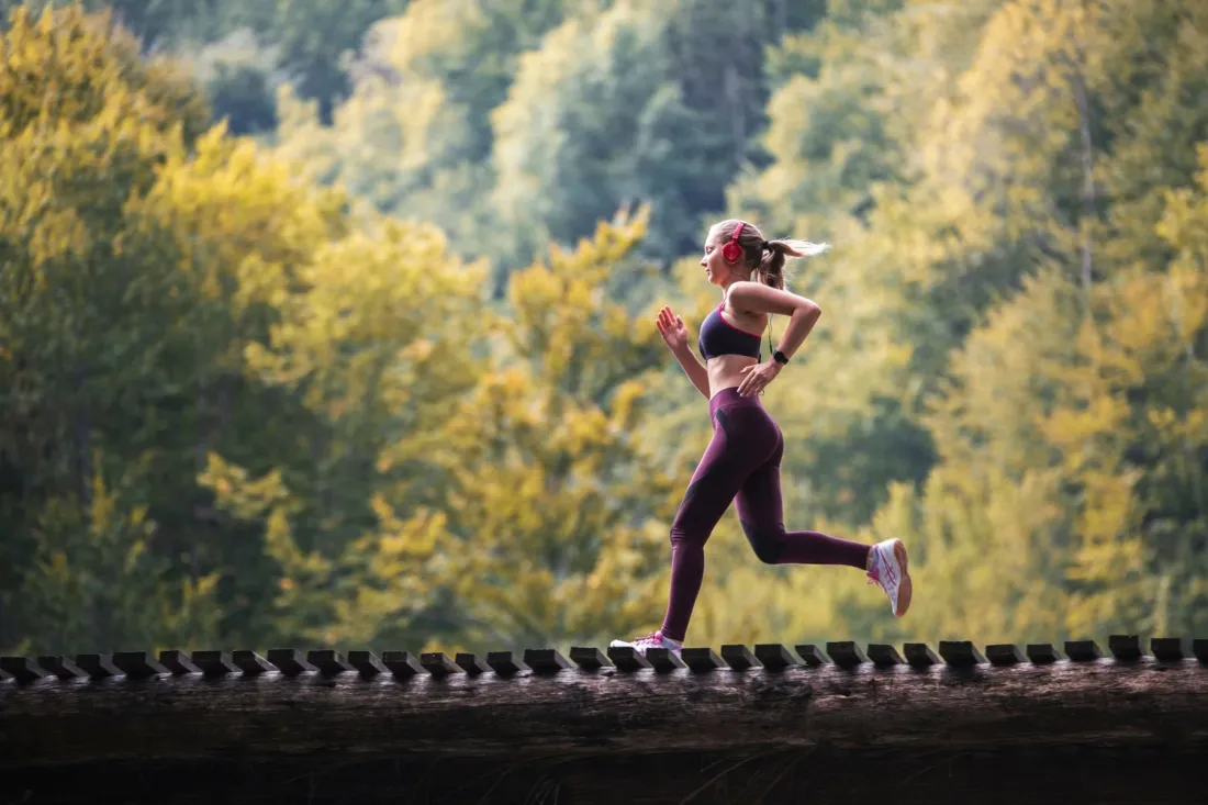 A woman running on a tree-lined trail, representing regenerative recovery