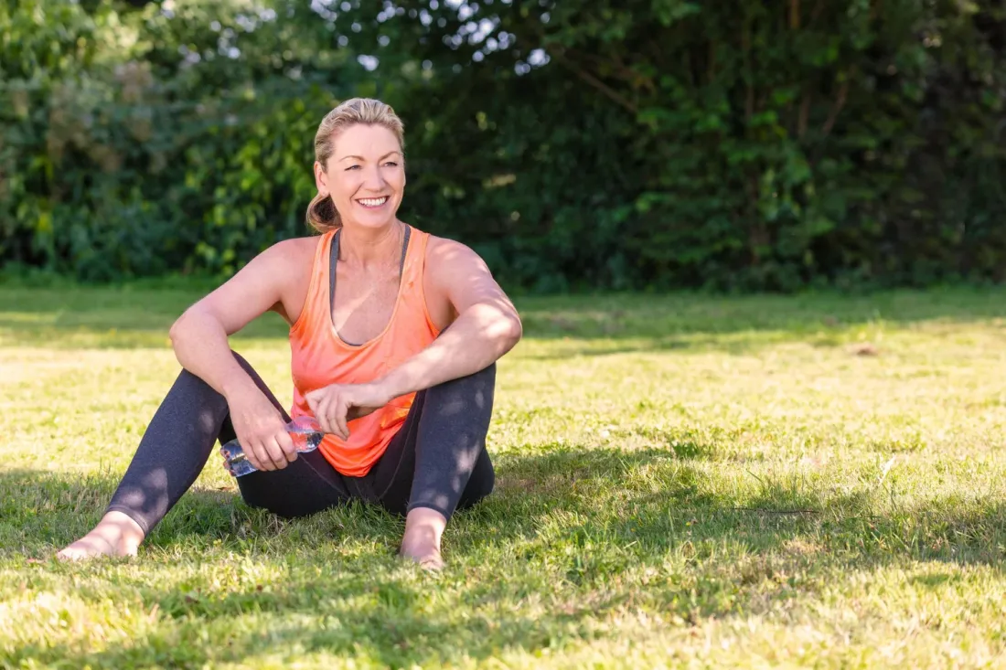A woman smiling outdoors after exercise
